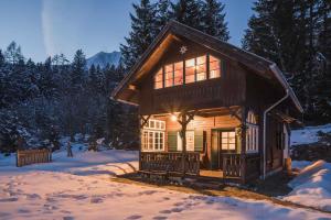 ein kleines Blockhaus im Schnee mit eingeschaltetem Licht in der Unterkunft 2 Chalets Innsbruck in Innsbruck