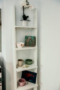 un estante de libros blanco con tazones y flores. en Apartament de lux ultramodern in zona centrala, en Timisoara