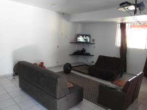 uma sala de estar com dois sofás e uma televisão em Pousada Sombra das Ondas em Guarapari