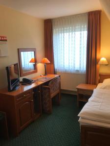 a hotel room with a bed and a desk with a mirror at HOTEL PÜNJER in Witzhave