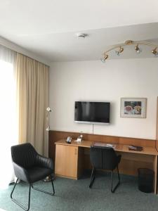 um quarto com uma secretária, uma televisão e 2 cadeiras em Hotel Occam em Munique