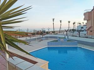 una gran piscina con palmeras en el fondo en Apartamentos Argenta Caleta 3000, en Peñíscola