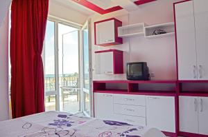 a room with a bed and a tv and a window at Akra Apartments in Chernomorets