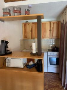 uma cozinha com armários de madeira e um micro-ondas branco em RESIDENCE UBAYE A 23 em Le Sauze