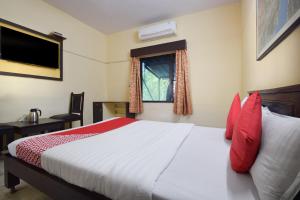 Un dormitorio con una cama con almohadas rojas y una ventana en OYO 24408 Nirmala Guest House, en Jodhpur