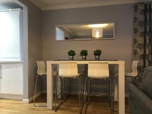 a dining room table with white chairs and a mirror at Flat One, 212 Eaglesham Road, East Kilbride, Glasgow in Glasgow
