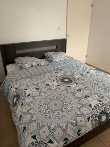 a bed with a blue and white comforter on it at logement entier vue sur mer in Gourbeyre