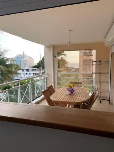 einen Balkon mit einem Holztisch und Stühlen auf einer Terrasse in der Unterkunft logement entier vue sur mer in Gourbeyre