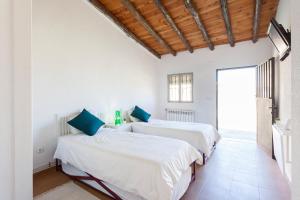 2 Betten in einem Zimmer mit weißen Wänden und blauen Kissen in der Unterkunft Albergue Sierra Norte in Manjirón