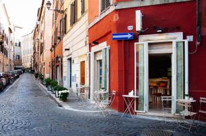 a red building with tables and chairs on a street at All'Orologio in Rome