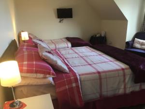 a bedroom with two beds and a tv on the wall at Rhenetra in Arisaig