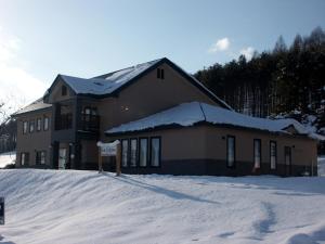 a building with a sign in the snow at Pension and Restaurant La Collina in Nakafurano