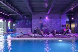 una piscina con sillas junto a una pared de ladrillo en Village Hotel Basingstoke, en Basingstoke