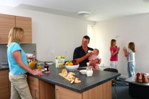 un hombre sosteniendo un bebé en una cocina con una familia en David Russell Apartments - Campus Accommodation en St Andrews