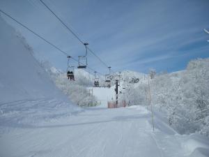 a ski lift on a snowy mountain with snow covered trees at Villa Komakusa in Hakuba