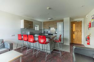 a kitchen with red chairs and a kitchen counter at David Russell Apartments - Campus Accommodation in St. Andrews