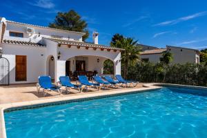 a villa with a swimming pool and blue chairs at Carpe Diem in Jávea