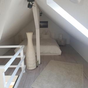 Cette chambre blanche comprend un lit et un vase. dans l'établissement 45 m² Maisonette-Wohnung in Uni-/Hauptbahnhofnähe, à Duisbourg