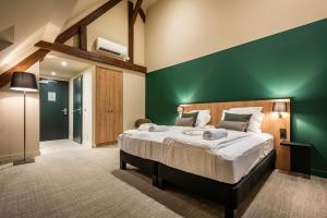una camera con un grande letto con una parete con accento verde di La Rochette a Labaroche