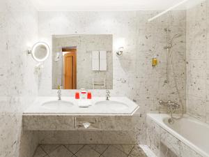 a bathroom with a sink and a tub and a mirror at DORMERO Hotel Halle in Halle an der Saale