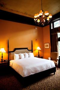 a bedroom with a bed and two chairs and a chandelier at Mansions on Fifth in Pittsburgh