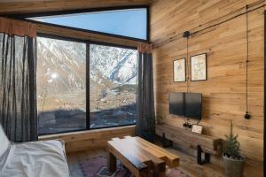 ein Wohnzimmer mit einem Tisch und einem großen Fenster in der Unterkunft Kazbegi cabins in Kazbegi