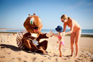 a woman and a child playing with a stuffed animal on the beach at Camping Le Petit Rocher in Longeville-sur-Mer