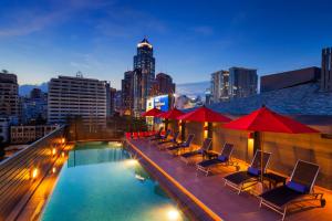 a rooftop pool with chairs and umbrellas on a building at Hotel Solo, Sukhumvit 2, Bangkok - SHA Extra Plus in Bangkok