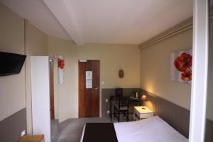 a bedroom with a bed and a table with a chair at Hotel De l'Univers in Caen