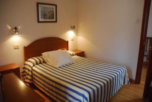 ein Hotelzimmer mit einem Bett mit einer gestreiften Decke in der Unterkunft HOTEL CARAVIA in Caravia