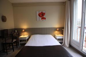 卡昂的住宿－尤尼維斯酒店，一间卧室配有一张床、两张桌子和两盏灯。
