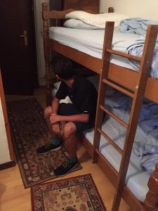 a boy sitting on the bottom bunk of a bunk bed at B&B LOKEV Sezana in Lokev