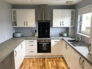 una cocina con armarios blancos y un aparato negro en Flat Five, 212 Eaglesham Road, East Kilbride, Glasgow en East Kilbride