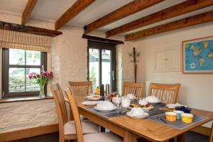 een eetkamer met een houten tafel en stoelen bij The White Cottage B&B in Saint Teath