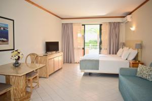 a hotel room with a bed and a tv and a couch at Clube Oceano Apartments in Albufeira