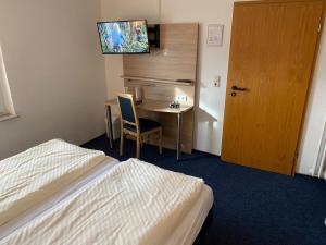 a hotel room with a bed and a table and a television at Motel Herbold in Knüllwald