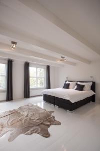 a white bedroom with a large bed and a rug at Mokum Suites in Amsterdam