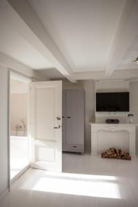 Cette chambre blanche dispose d'une porte et d'une télévision. dans l'établissement Mokum Suites, à Amsterdam