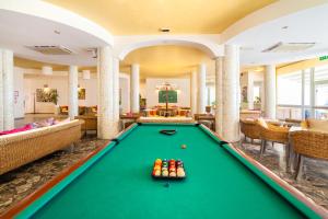 a pool table in a hotel lobby with couches at Hotel American in Lignano Sabbiadoro