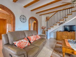 a living room with a brown leather couch and stairs at Villa Robinson by Interhome in Pedreguer