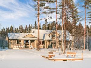 a house in the snow with benches in front of it at Holiday Home Villa puronotko by Interhome in Pertunmaa