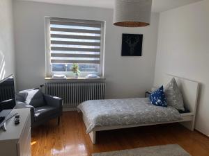 a bedroom with a bed and a chair and a window at Modern CITY Apartments in Kaiserslautern