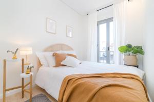 a white bedroom with a large bed and a window at Casa Boma Lisboa - Modern & Luminous Apartment with Balcony - Alcantara I in Lisbon