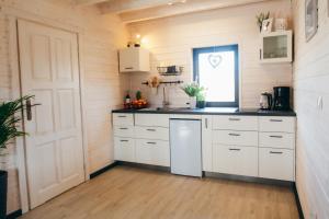kuchnia z białymi szafkami i oknem w obiekcie Rozmaryn w mieście Bierna