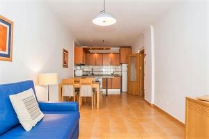 a living room with a blue couch and a kitchen at Veleiro Verde in Monte Gordo