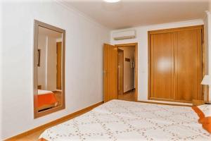 - une chambre avec un grand lit et un miroir dans l'établissement Veleiro Verde, à Monte Gordo