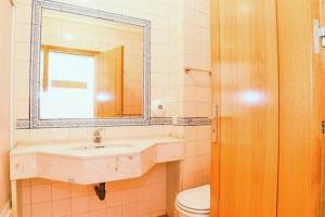 a bathroom with a sink and a toilet and a mirror at Veleiro Verde in Monte Gordo