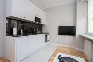 cocina con armarios blancos y TV de pantalla plana en CR Apartament przy Katedrze, en Białystok