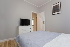 biała sypialnia z łóżkiem i telewizorem z płaskim ekranem w obiekcie CR Apartament przy Katedrze w mieście Białystok