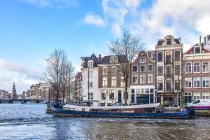 a boat on a river in front of buildings at Amsterdam Canal Guest Apartment in Amsterdam